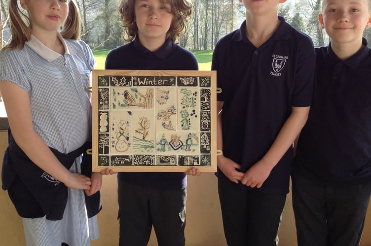 Some of the St German Primary School pupils with a framed arrangement of the pottery tiles they have made.