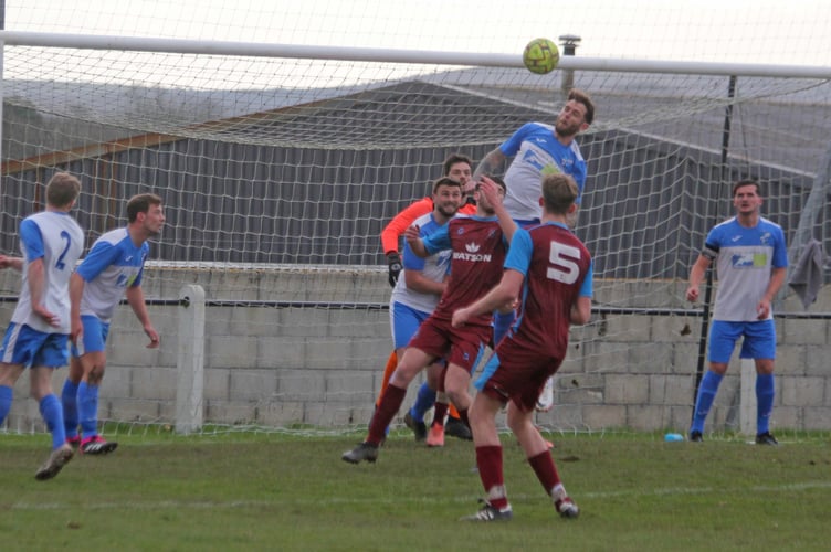 Camelford striker Mark Gusterson heads the ball clear.