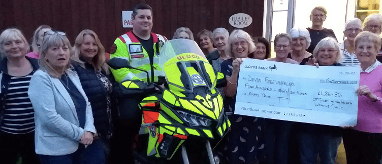 Members of St Giles on the Heath Women’s Guild present a cheque for £486.80 to Tony Ewens of Devon Freewheelers