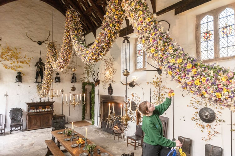 Final flowers added to the Christmas garland in the Great Hall at Cotehele, Cornwall. Credit National Trust Images, James Beck.