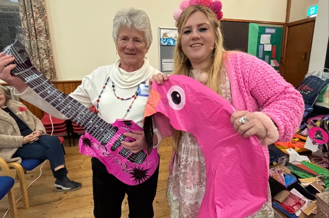 WI president Cynthia May playing a discarded plastic guitar and Kate, Flotsam Flo, holding a rubbished flamingo